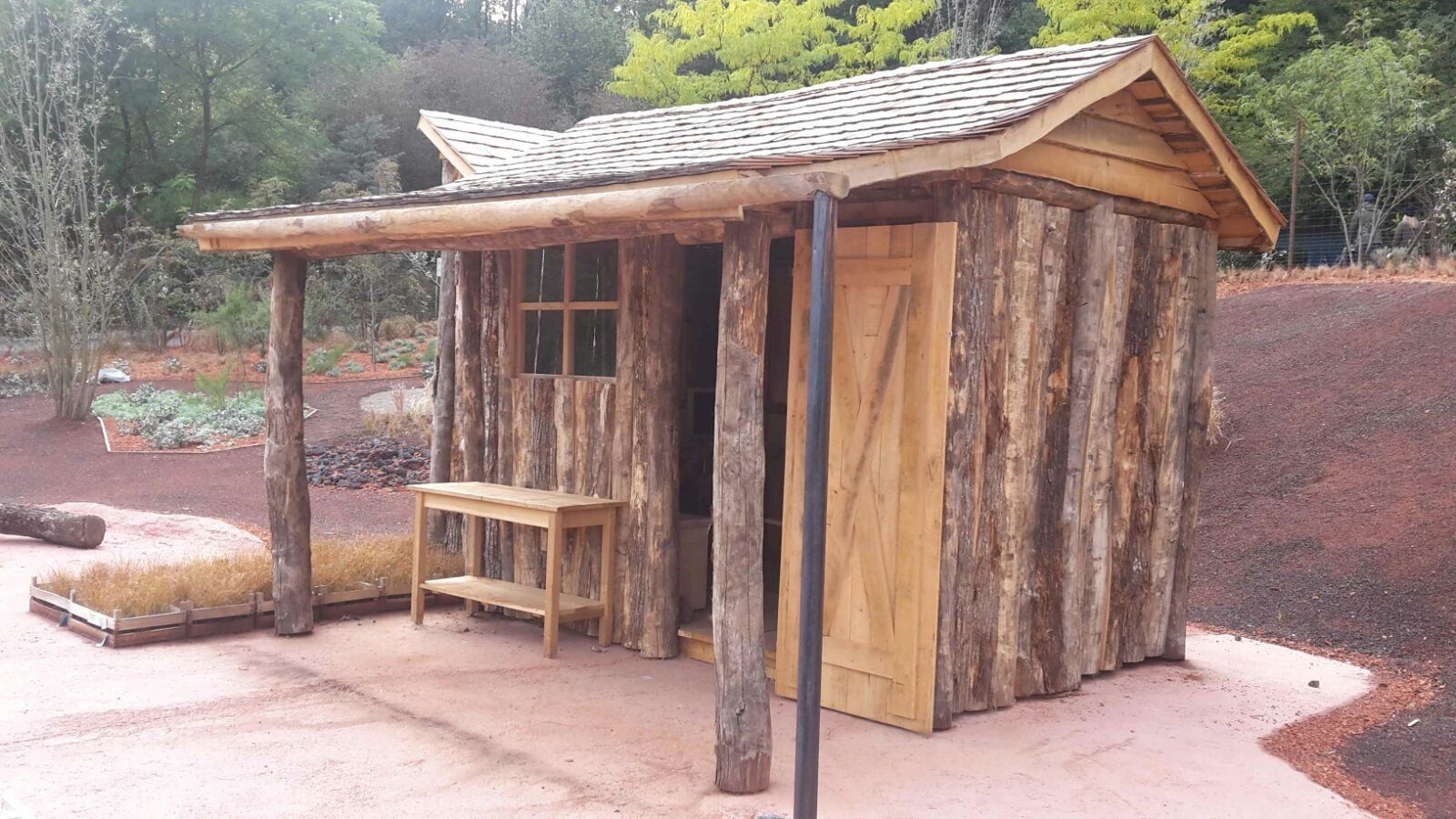 Ein kleiner Holzschuppen mit einem Dach aus Baumstämmen