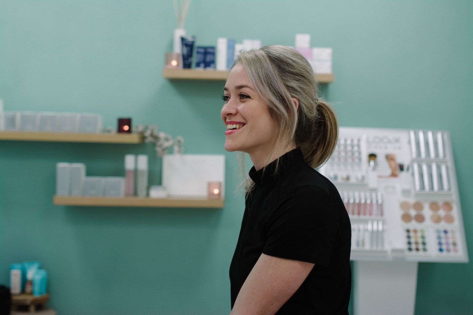 Een vrouw in een zwart shirt lacht in een schoonheidssalon.