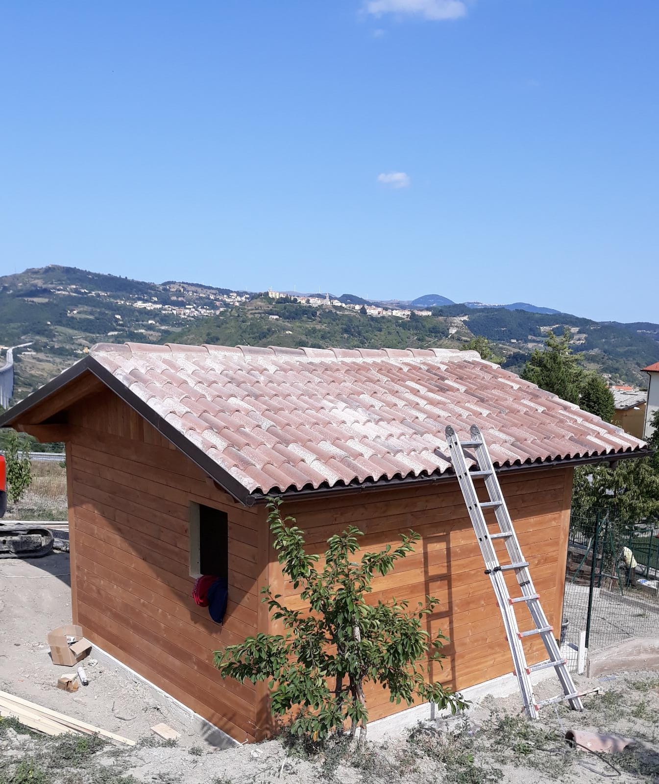Una piccola casa di legno con una scala sul tetto
