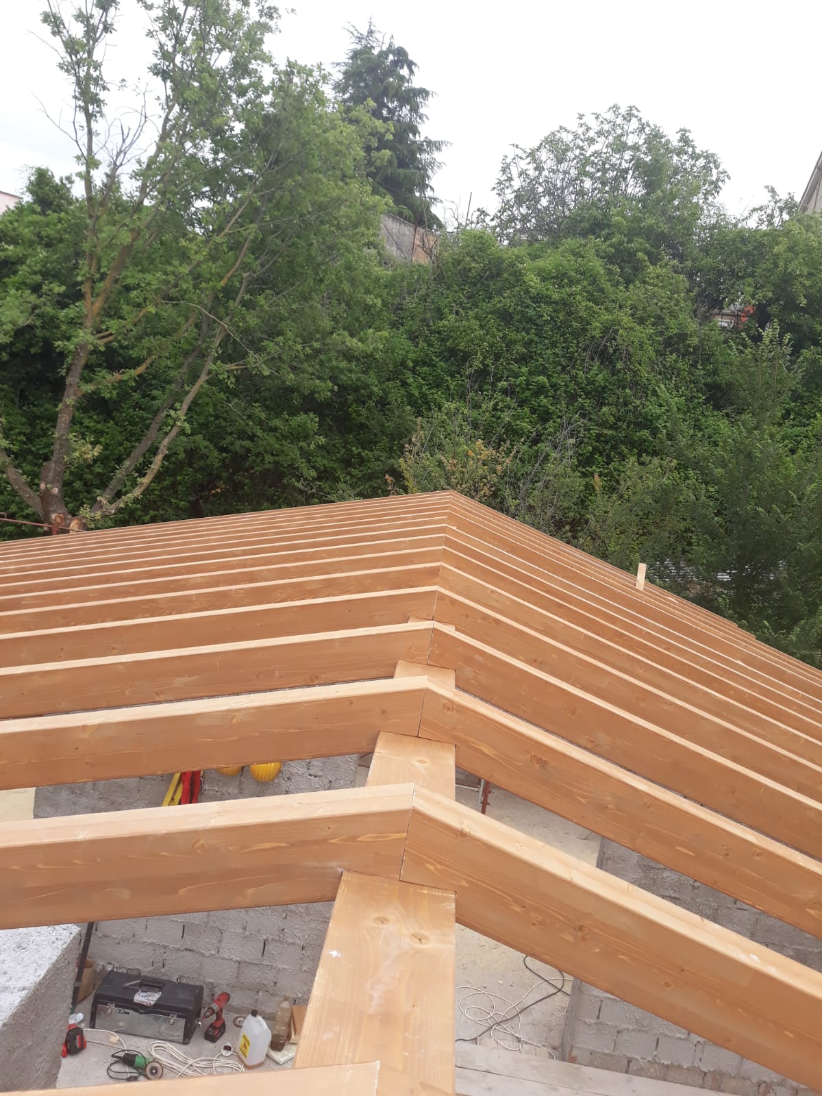 Si sta costruendo un tetto di legno con degli alberi sullo sfondo.