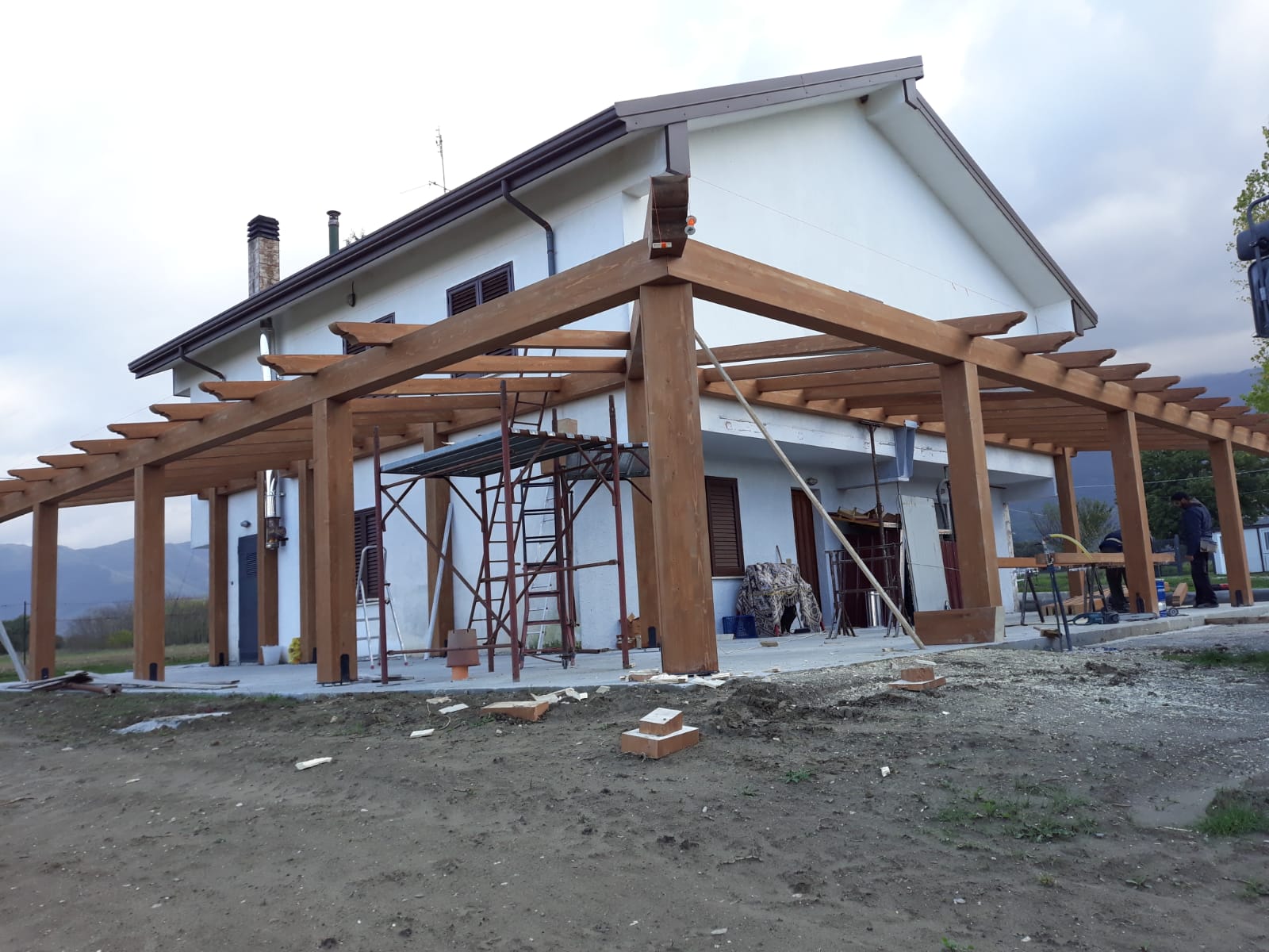 Una casa bianca con un pergolato di legno davanti