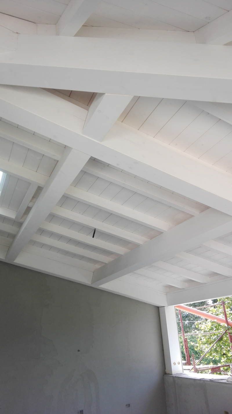 Il soffitto di una stanza con travi bianche e una finestra.