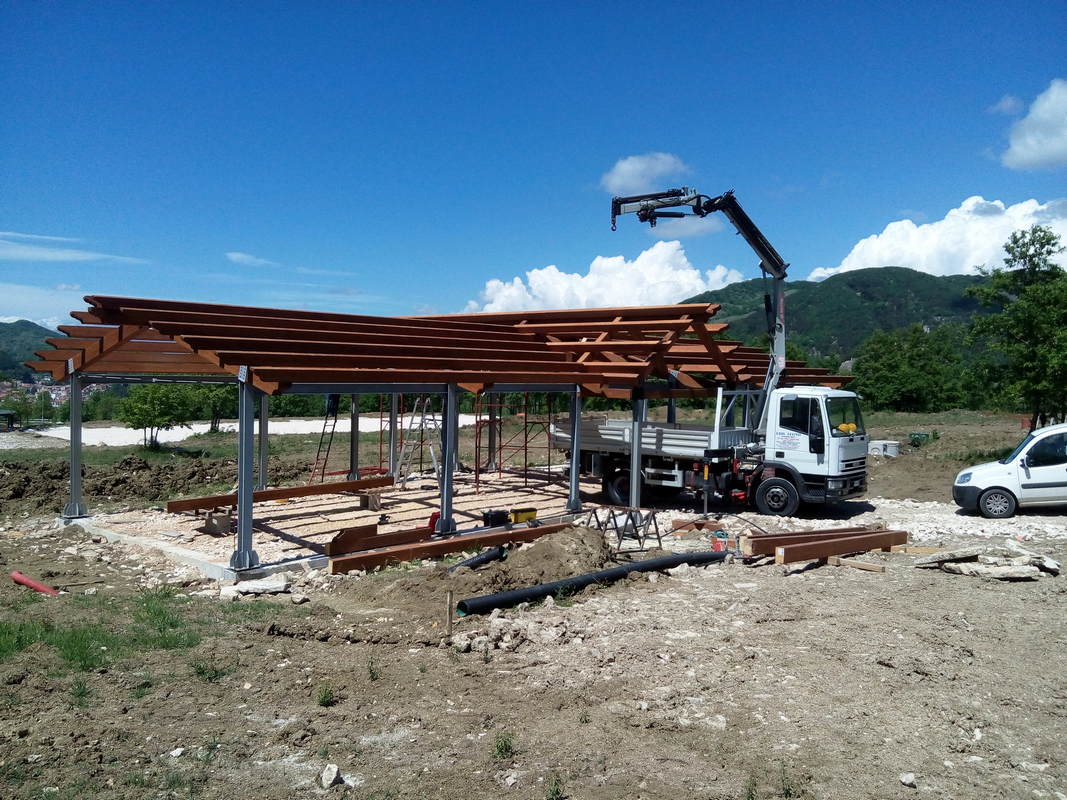 Una gru sta sollevando una struttura di legno in un campo.