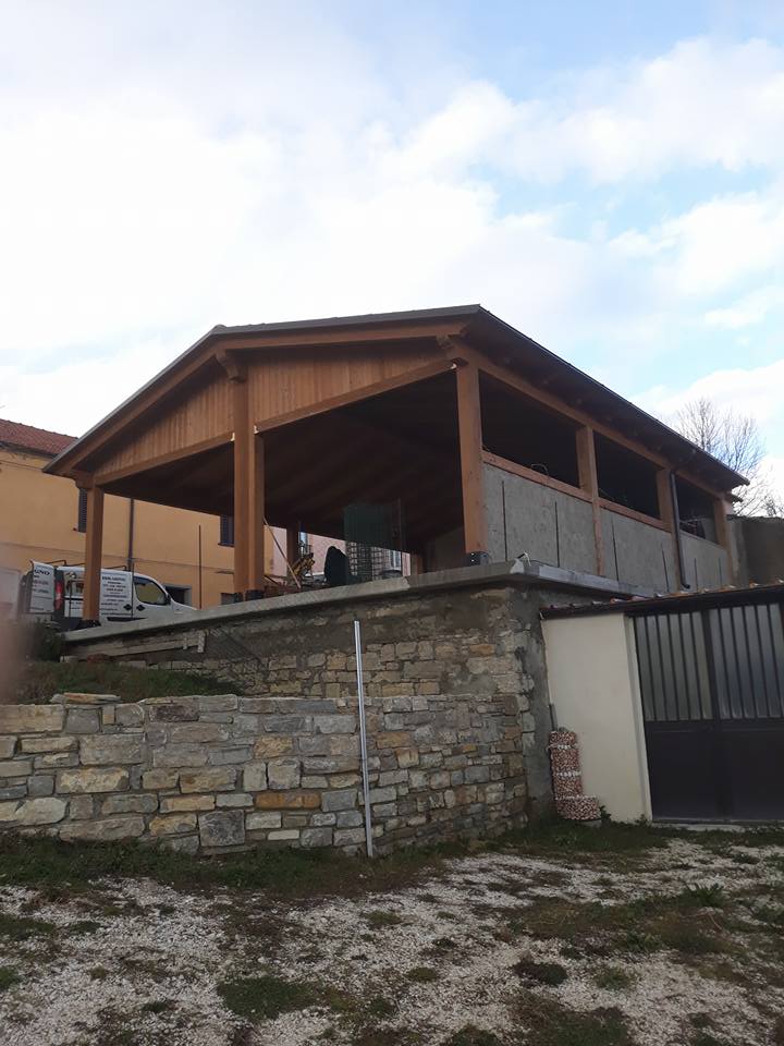 Un edificio con un tetto in legno è accanto a un muro di pietra