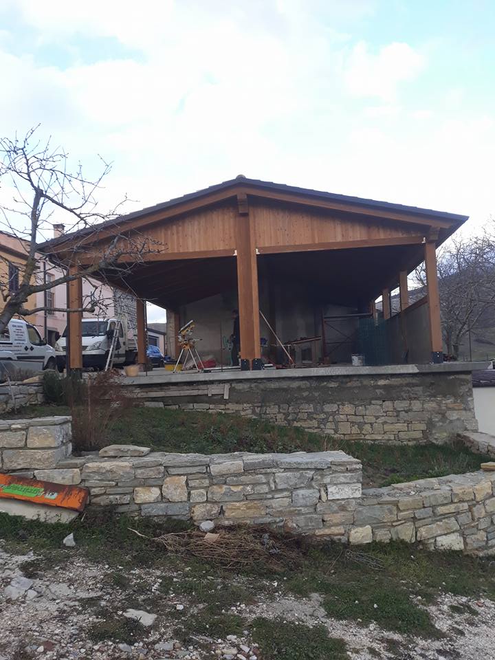 Un padiglione di legno viene costruito in mezzo a un muro di pietra.