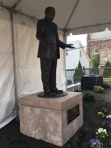 A statue of a man in a suit is standing in front of a tent.