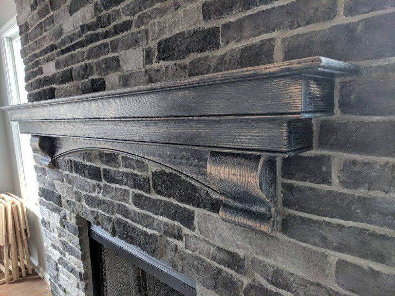 A brick fireplace with a wooden mantle in a living room.