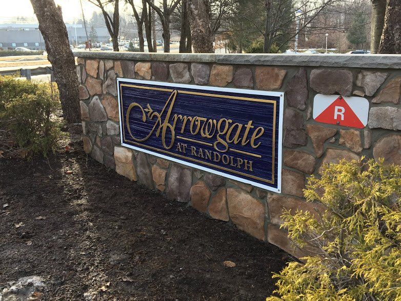 A sign on a stone wall that says arrowgate at randolph