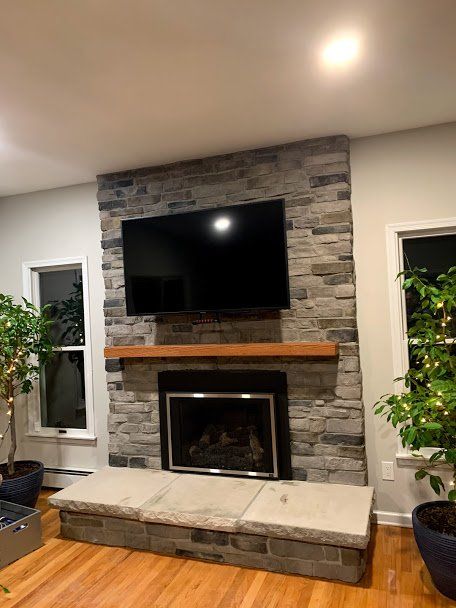 A living room with a fireplace and a flat screen tv on the wall.