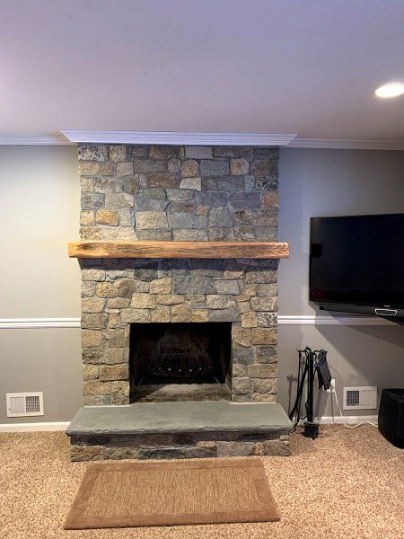 A living room with a stone fireplace and a flat screen tv.