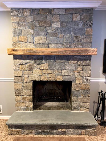 A stone fireplace with a wooden mantle in a living room.