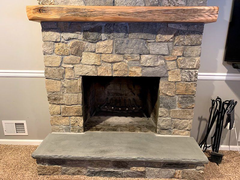 A stone fireplace with a wooden mantle in a living room.
