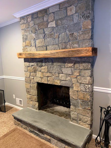 A stone fireplace with a wooden mantle in a living room.