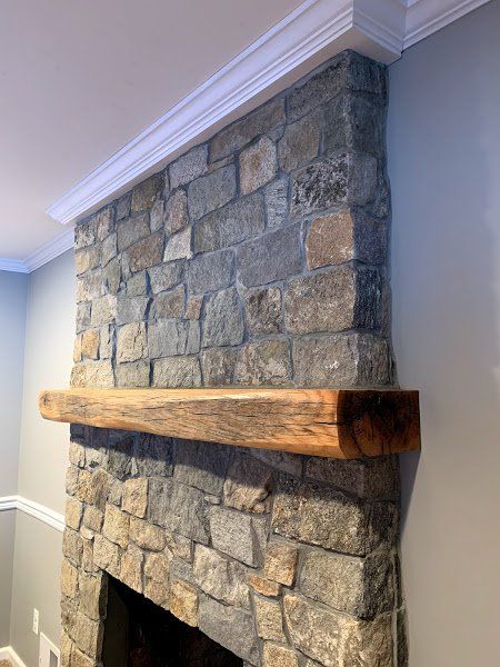 A stone fireplace with a wooden mantle in a living room.