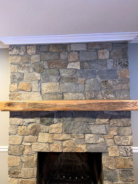 A stone fireplace with a wooden mantle in a living room.