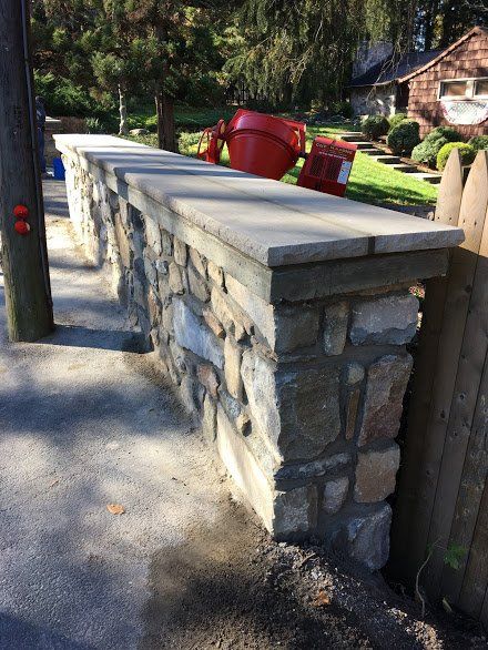 A stone wall is being built in front of a house.
