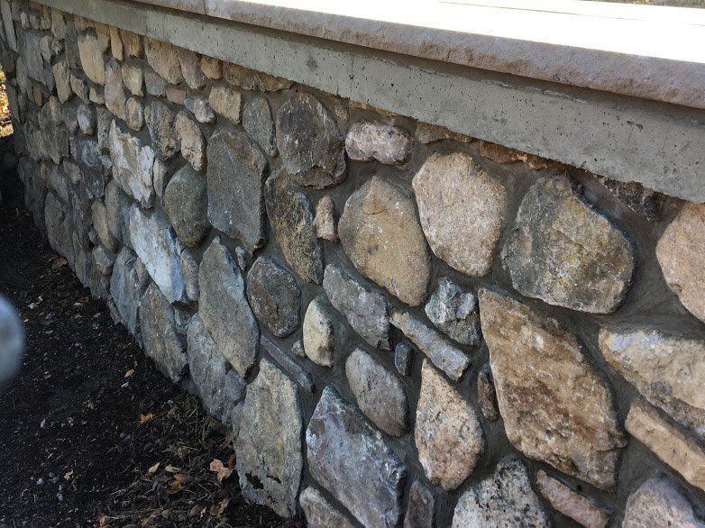 A close up of a stone wall with a concrete foundation.