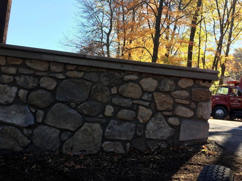 A red truck is parked next to a stone wall