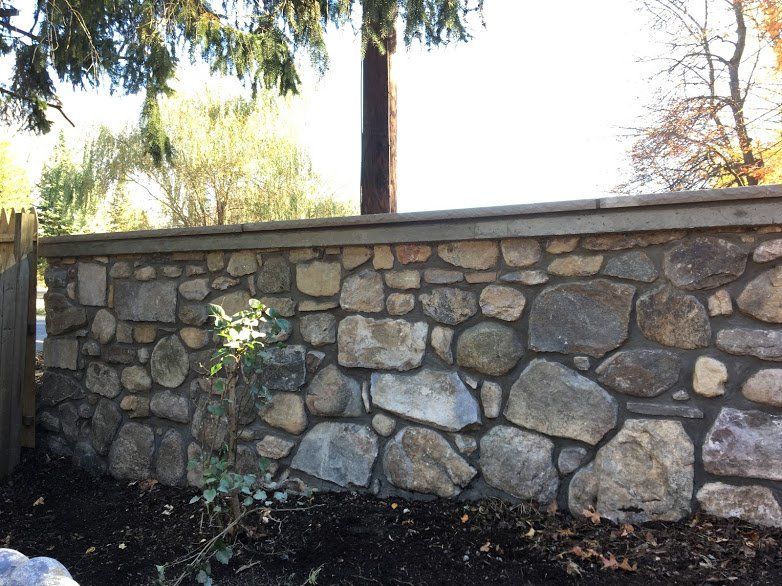A stone wall with a wooden fence in the background