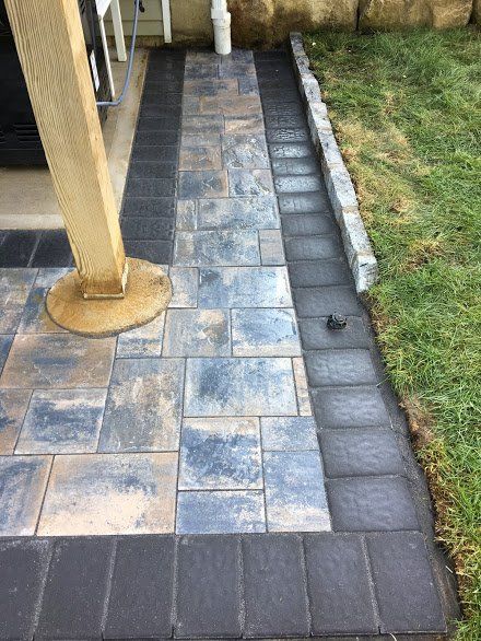 A walkway made of bricks is being built next to a lawn.
