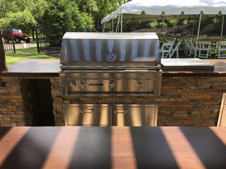 A stainless steel grill with a white tent in the background
