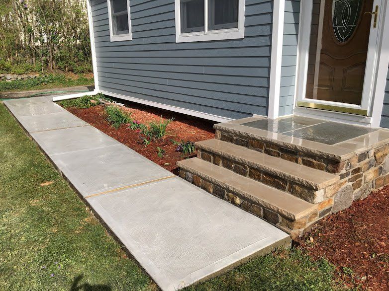 A concrete walkway leading to the front door of a house.