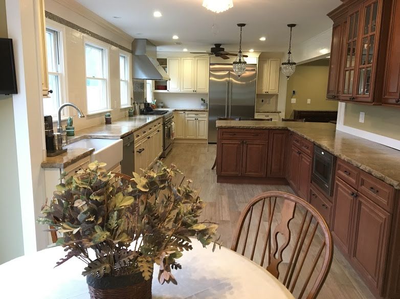 A kitchen with a table and chairs and a vase of flowers on the table.