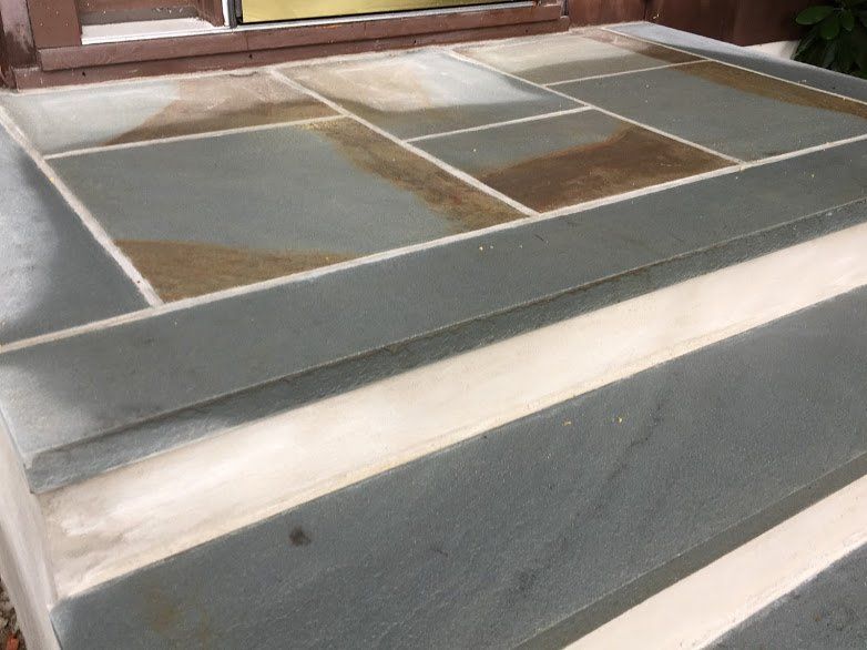 A close up of a tiled floor with steps leading up to a door.