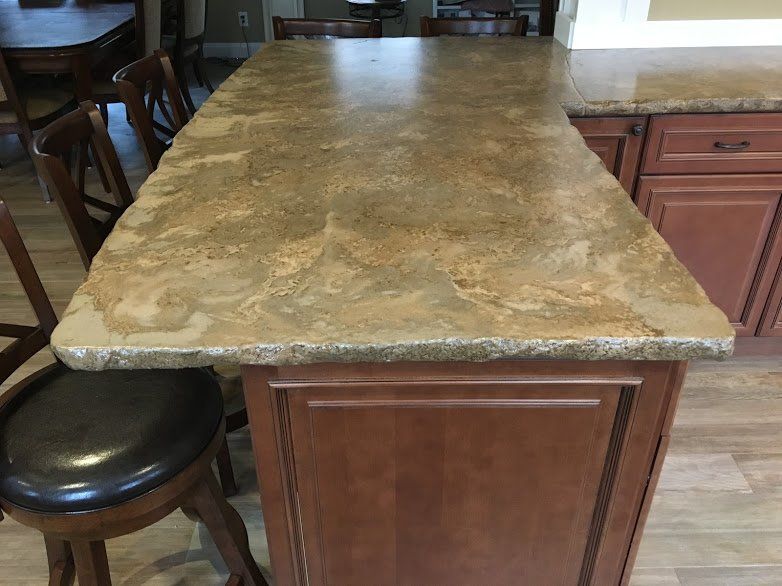 A kitchen island with a granite counter top and wooden cabinets.