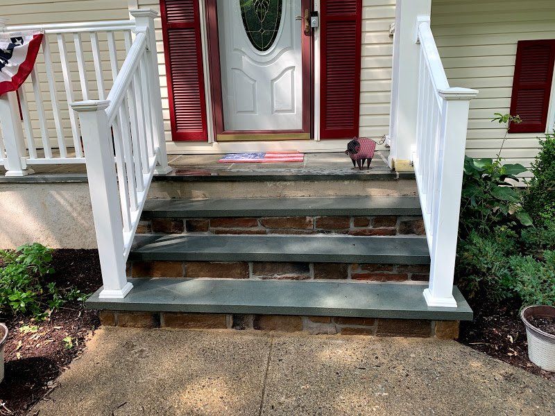 The front porch of a house with stairs and a white railing.