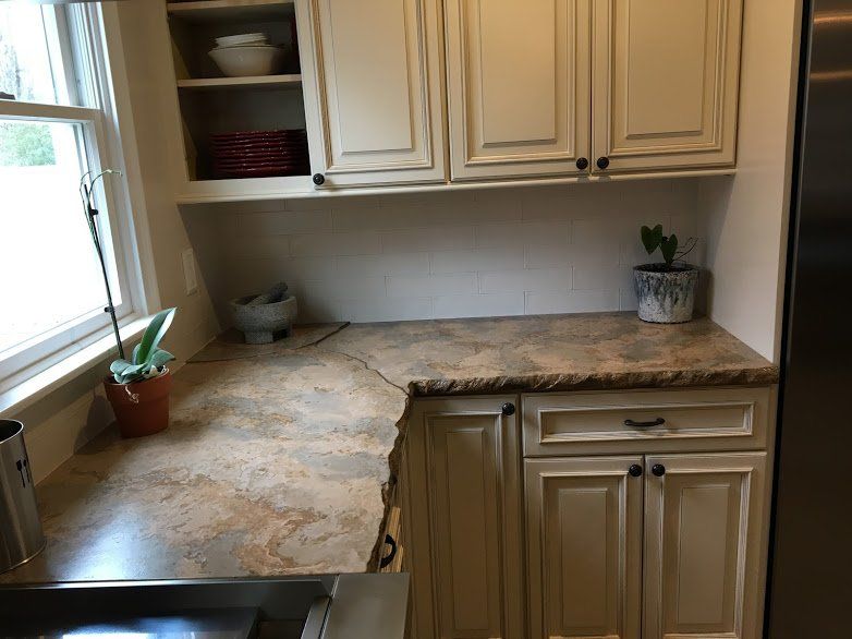 A kitchen with white cabinets and a marble counter top