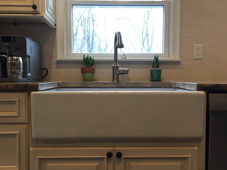 A kitchen sink with a faucet and two potted plants on the counter.