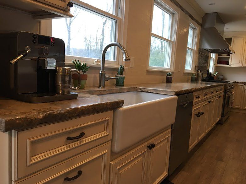 A kitchen with a farmhouse sink , stainless steel appliances , and white cabinets.
