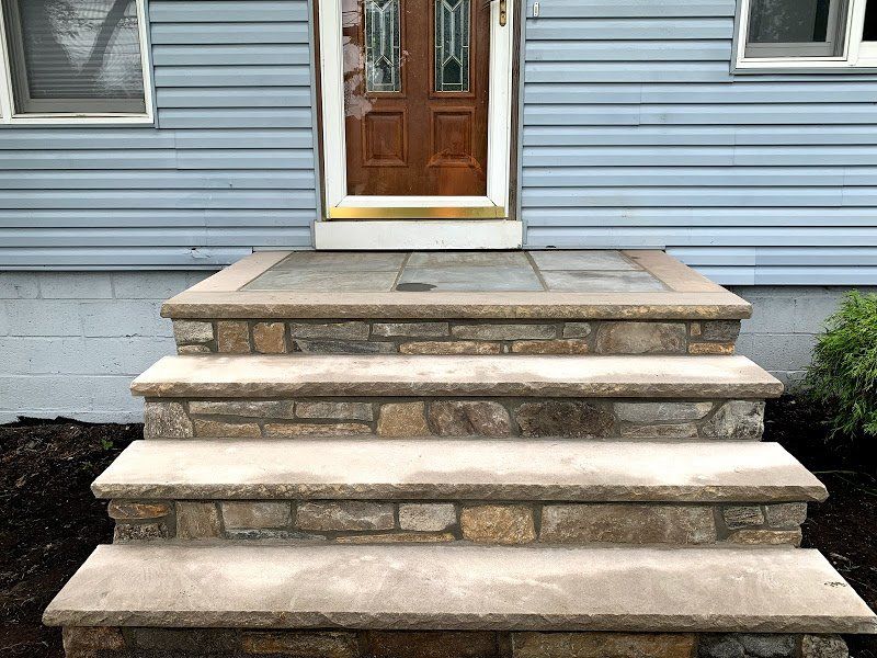 A blue house with stone steps leading up to the front door