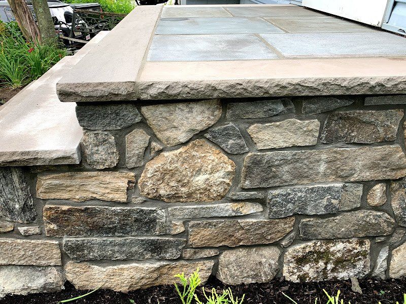 A stone wall with steps leading up to it next to a house.