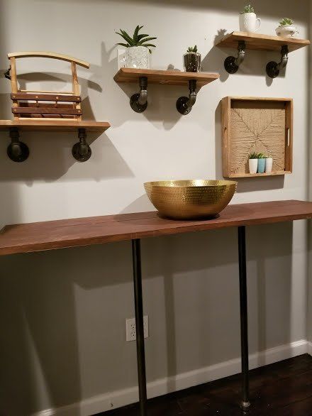 A wooden table with a bowl on top of it in a room with shelves.