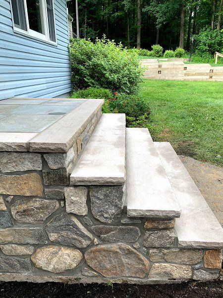A stone porch with steps leading up to a blue house.
