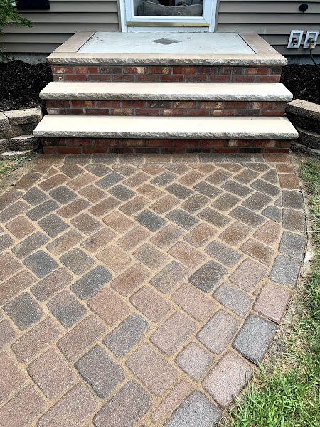 A brick walkway with stairs leading up to a house.