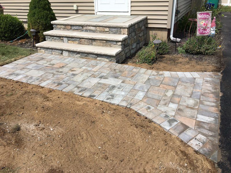 A stone walkway is being built in front of a house.