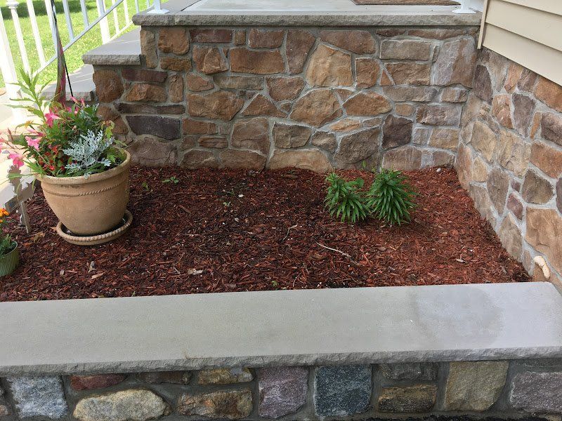 A stone wall with a potted plant in front of it.