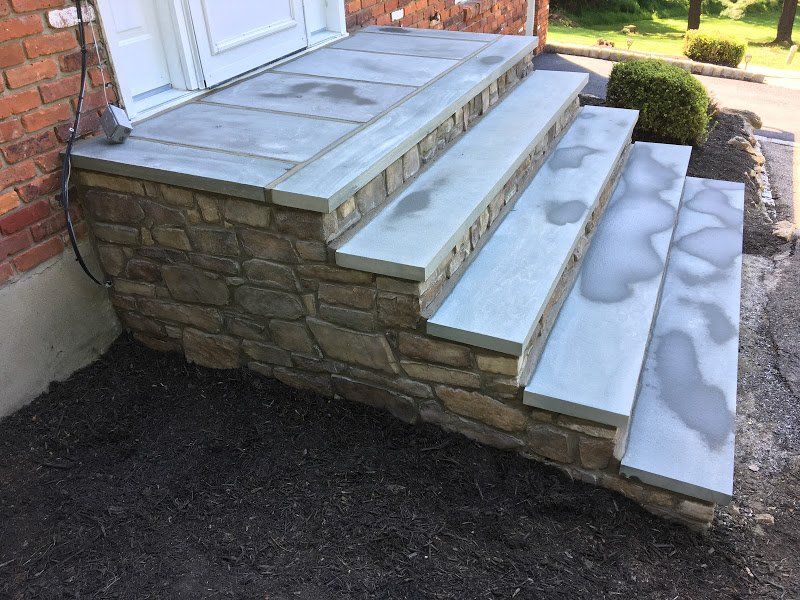 A stone porch with stairs leading up to a door.