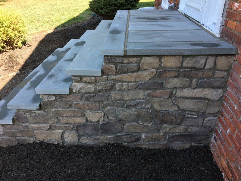 A stone porch with steps and a stone wall
