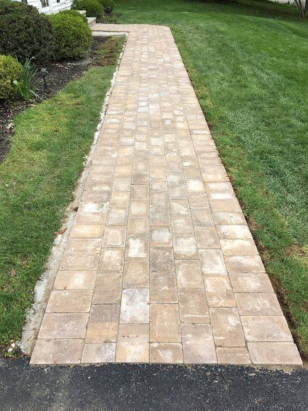 A brick walkway leading to a lush green lawn.