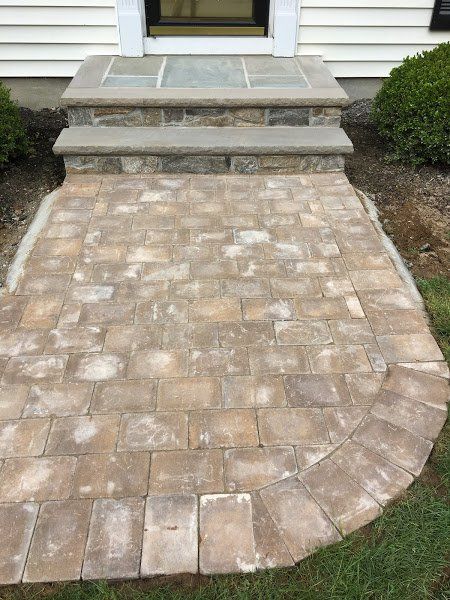 A stone walkway with steps leading to the front door of a house.