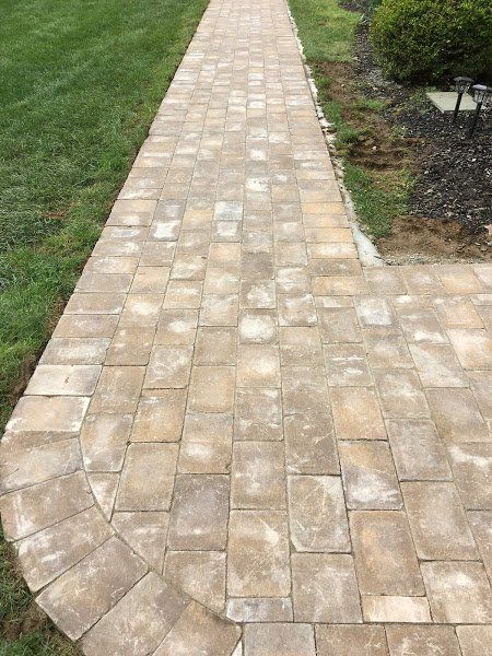 A brick walkway leading to a lush green lawn.