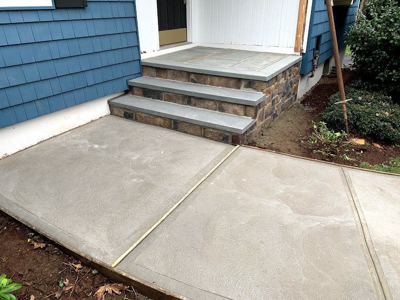 A concrete walkway with stone steps leading up to a house.