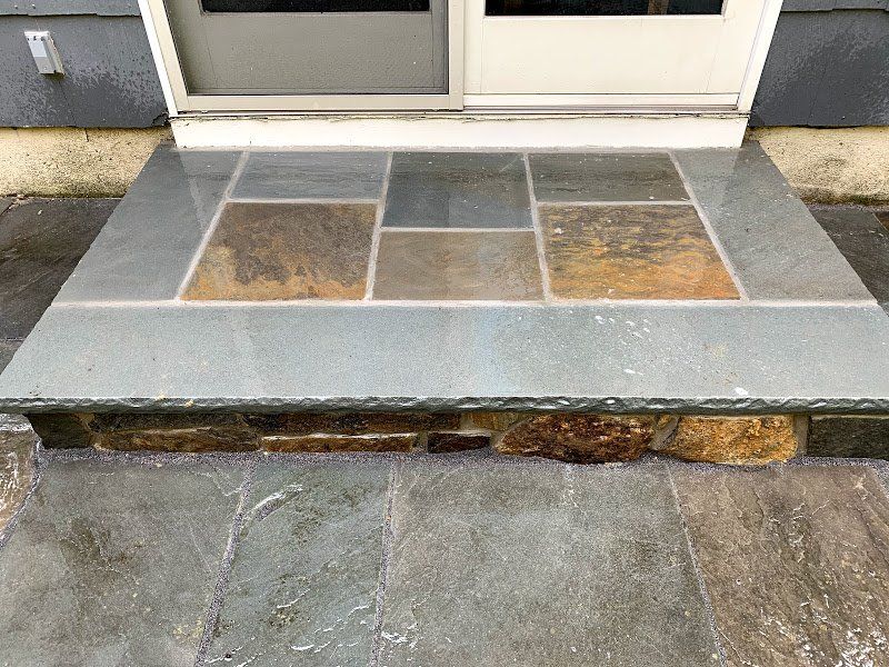 A stone porch with steps leading to a door.
