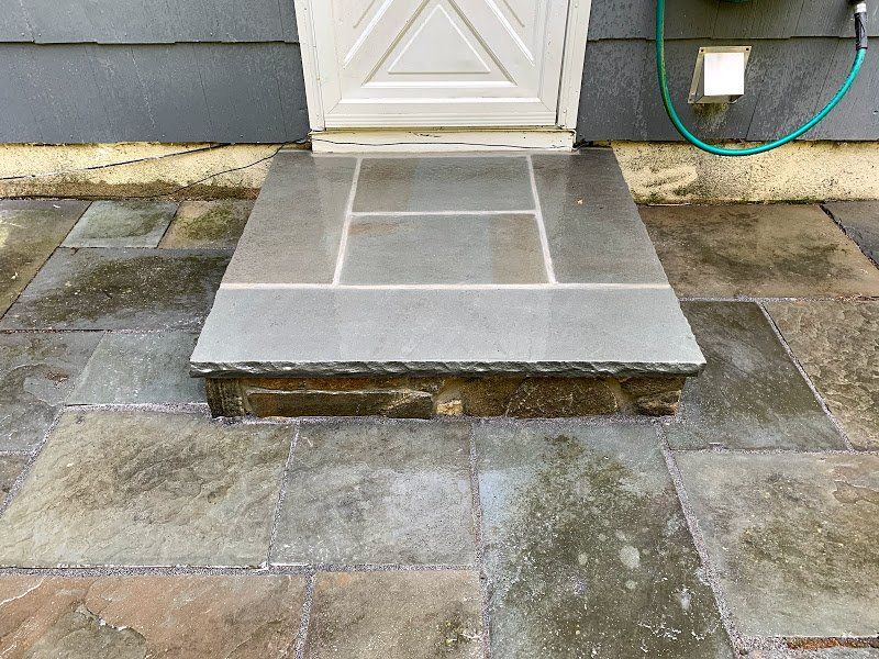 A stone walkway leading to a door with a hose attached to it.
