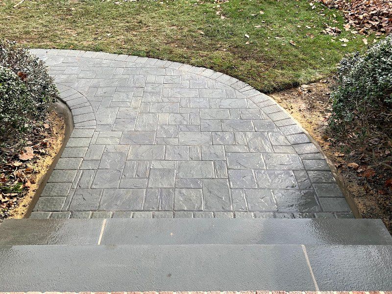 A brick walkway with stairs leading up to a grassy area.