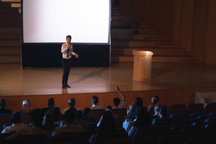 Man speaking to crowd in large auditorium